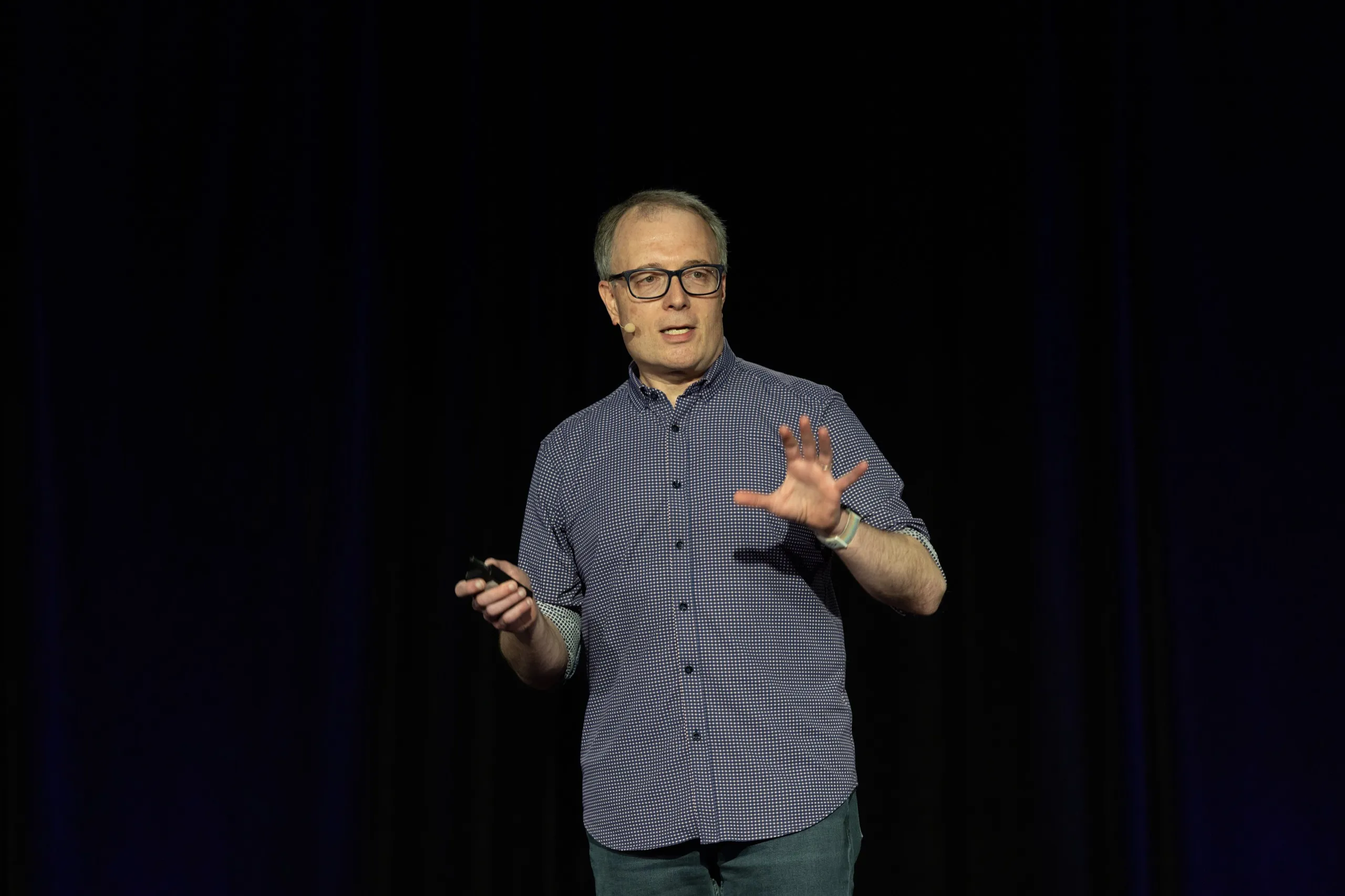 Ian Lurie mid-talk on a conference stage, hands out, mid-point